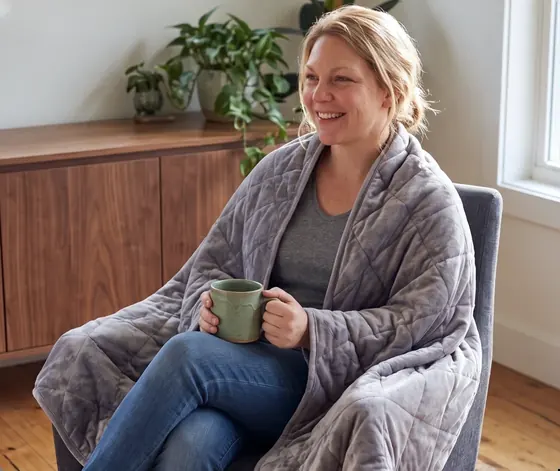 Official Velin image of an adult seated with a grey weighted blanket
